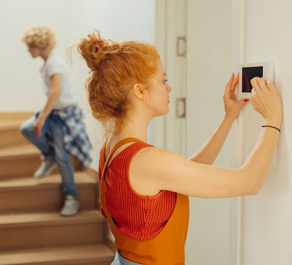 curly red haired woman in red tank top using thermostat